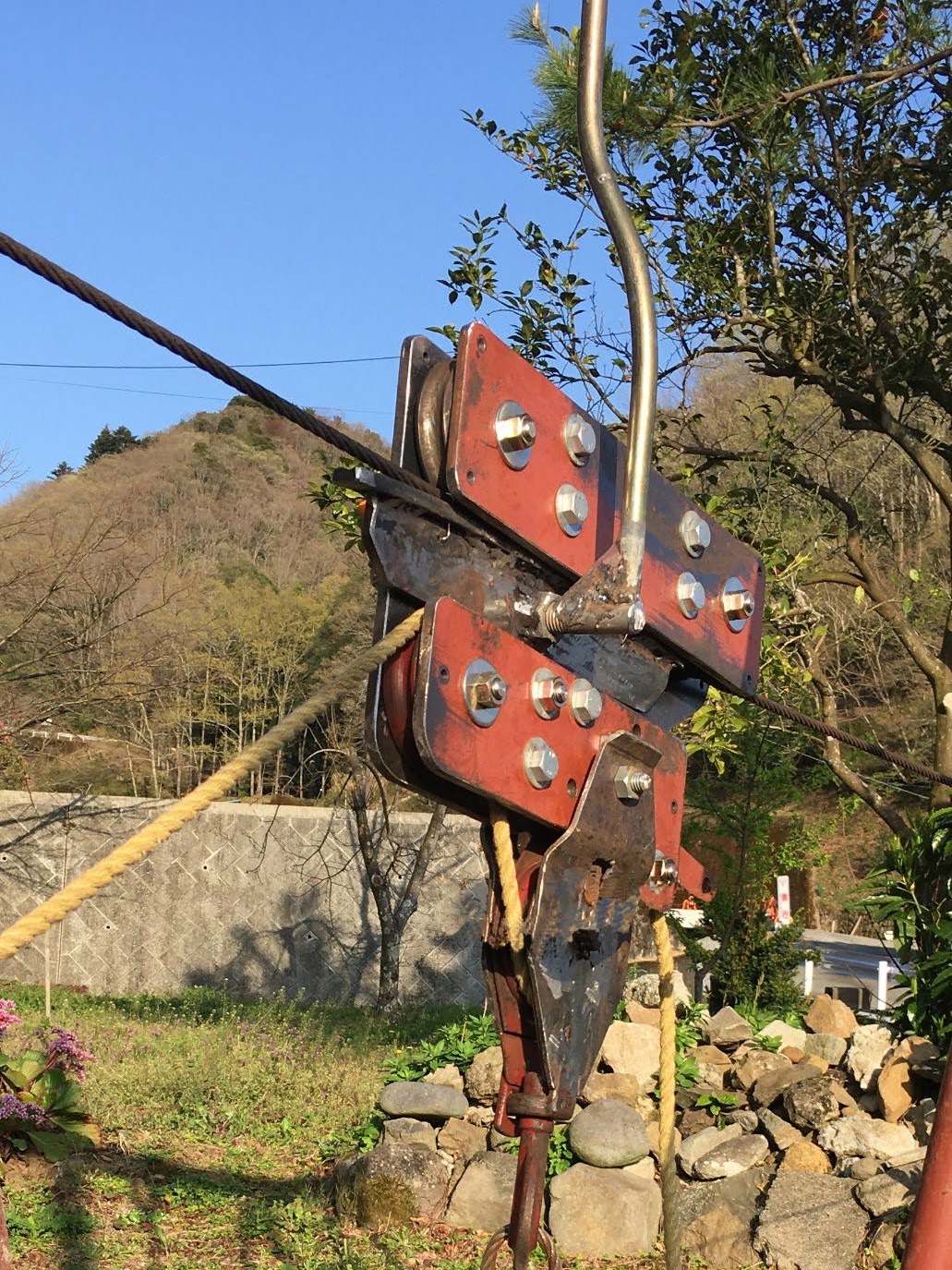 架線に取りつけた簡易架線集材の搬器。赤い板をボルトで留めた滑車と、ロープ